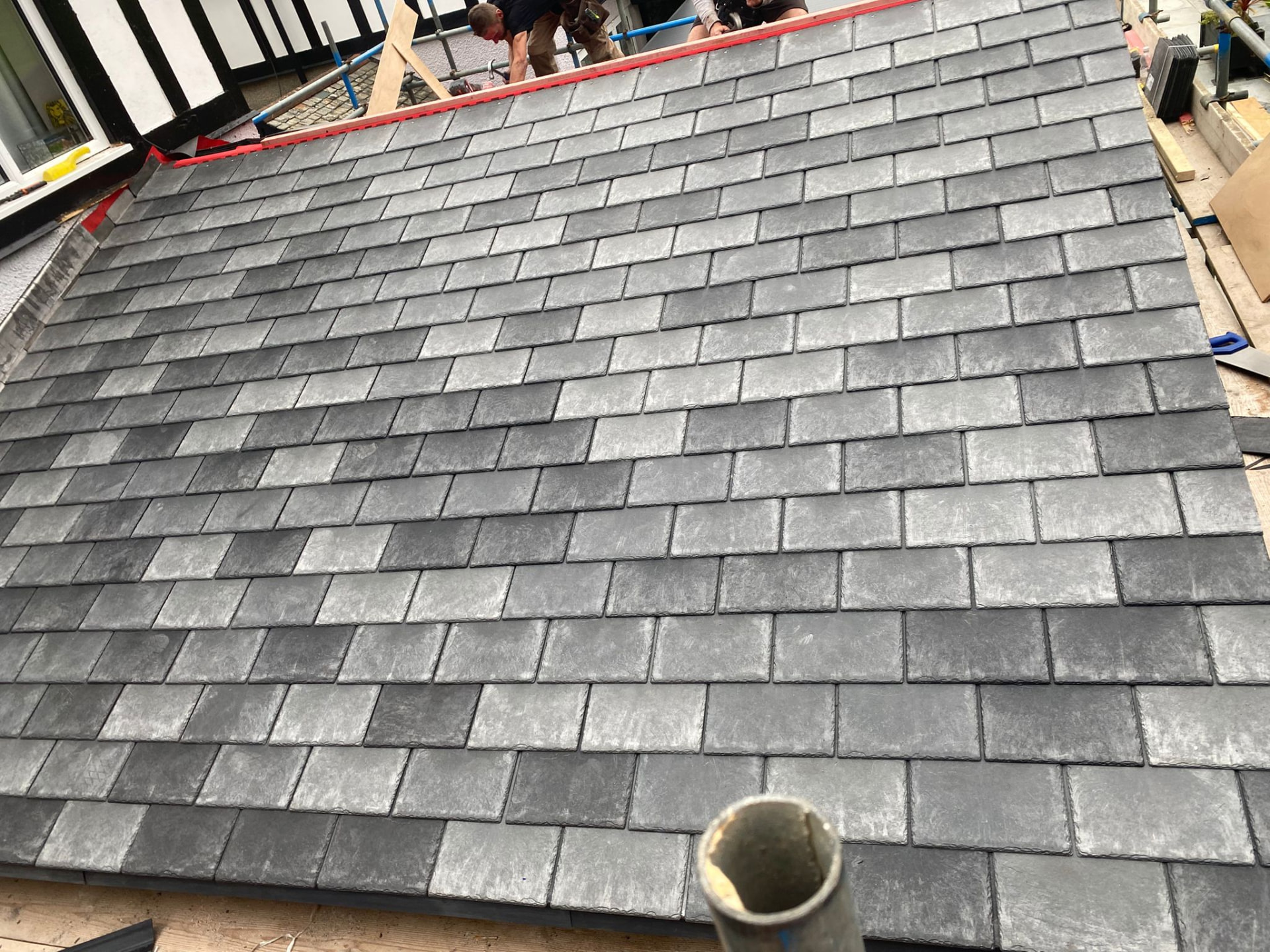 Roofers laying new Welsh slate tiles on a re-roof in North Wales