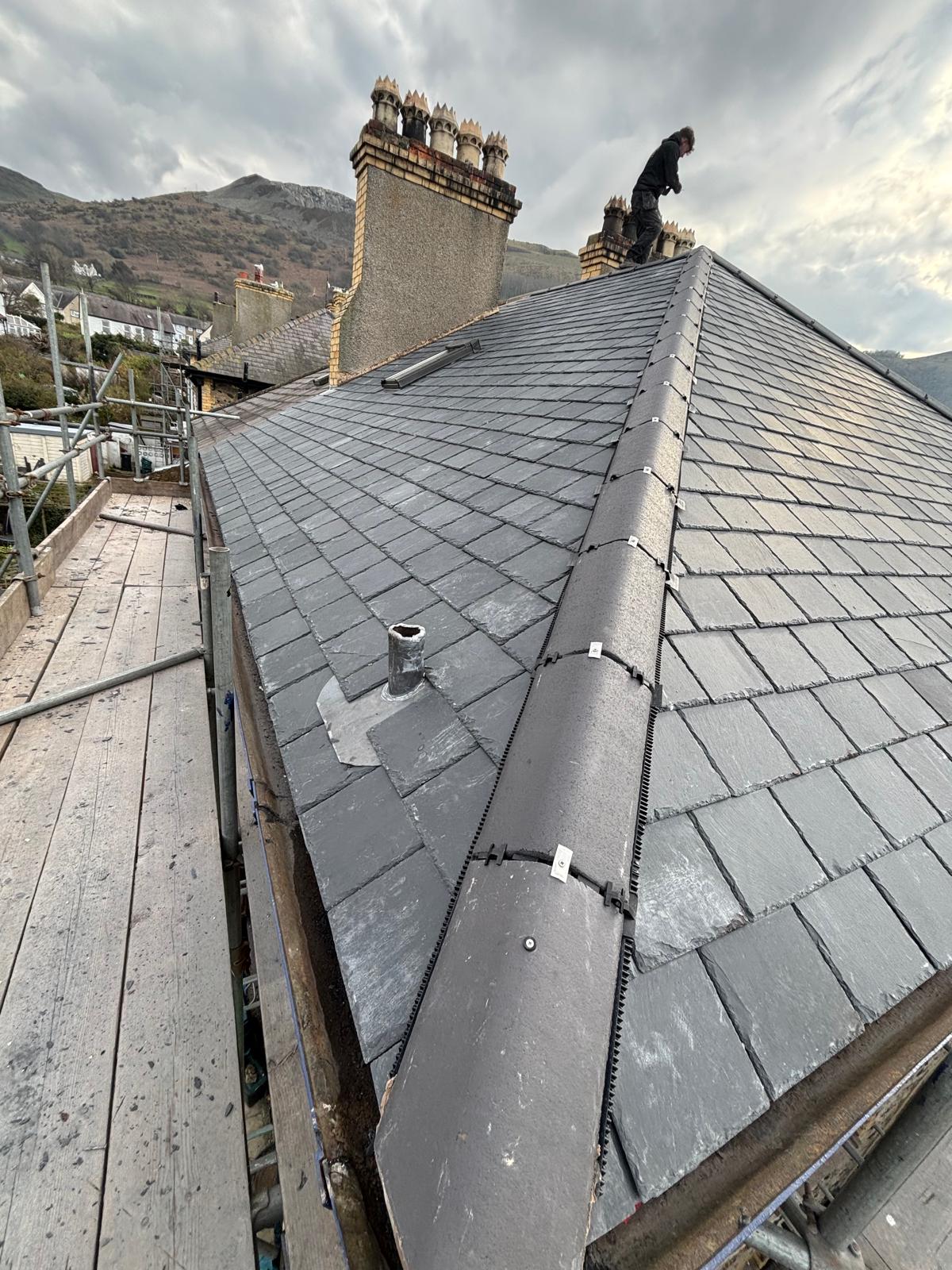 Completed natural slate roof with neat ridge tiles and lead detailing