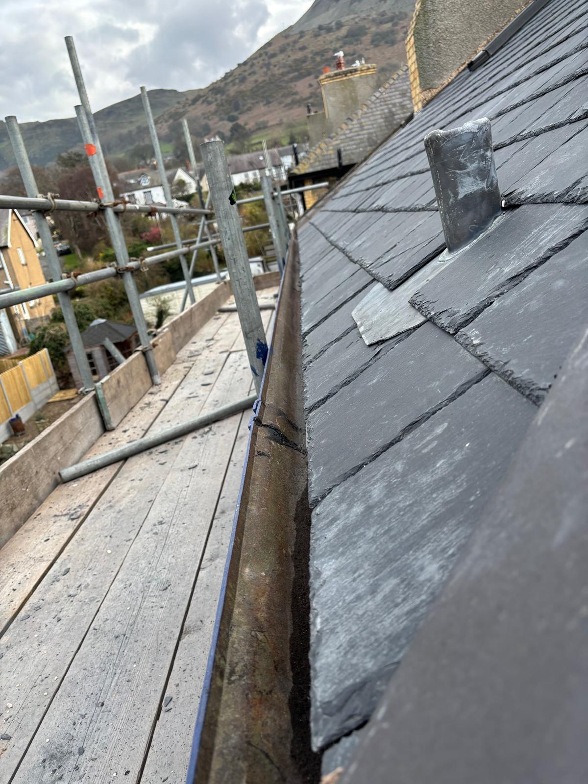Completed natural slate roof with neat ridge tiles and lead detailing