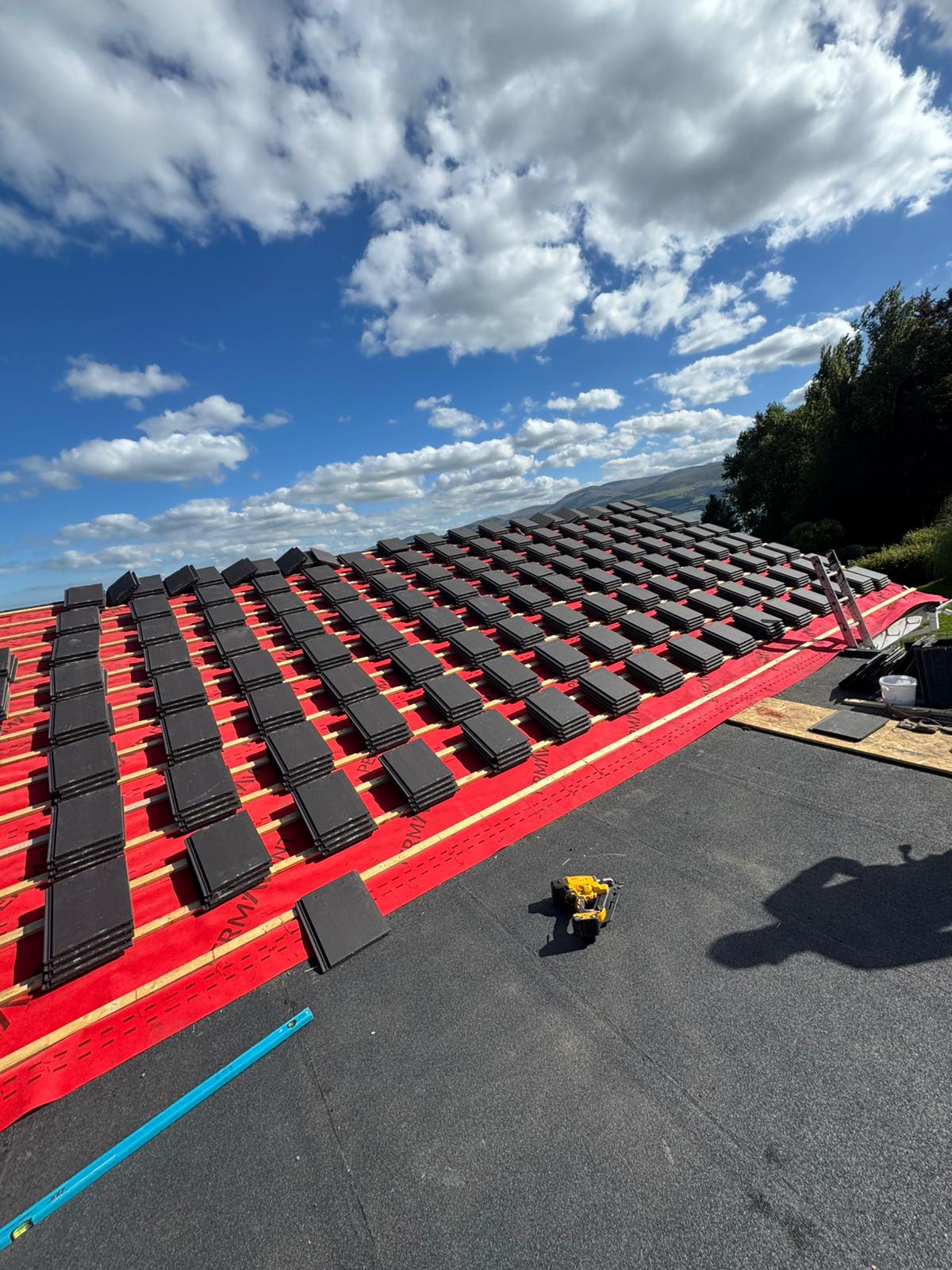 New roof tiles being laid over fresh battens and membrane on a full roof replacement