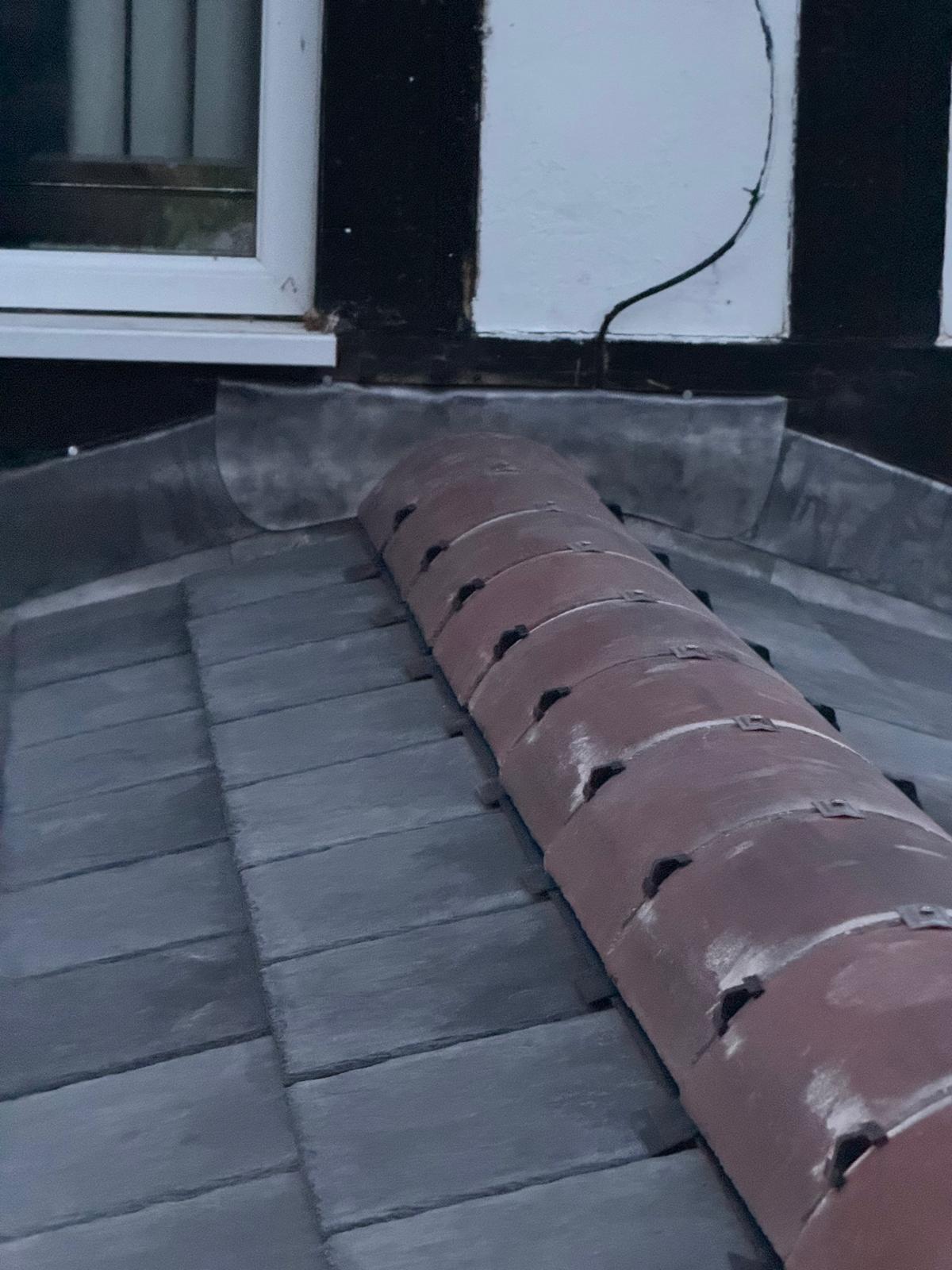 Completed natural slate roof with neat ridge tiles and lead detailing